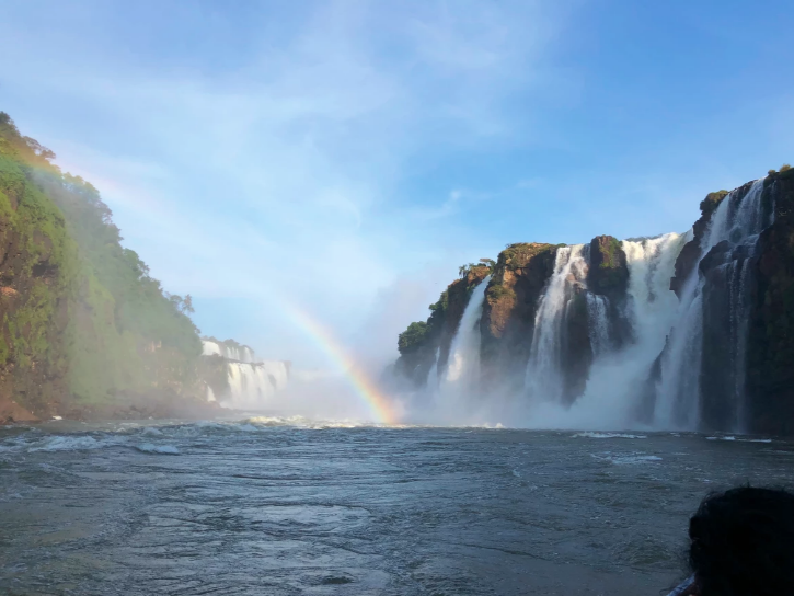 rainbow next to iguazu falls from the water