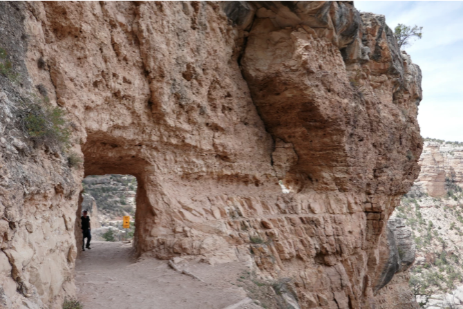 narrow cliff paths with a natural stone doorway through red rock