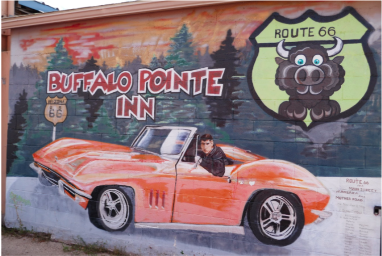 painted street art of an orange car on the side of an inn