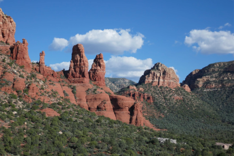 two columned red rock structure surrounded by green foliage