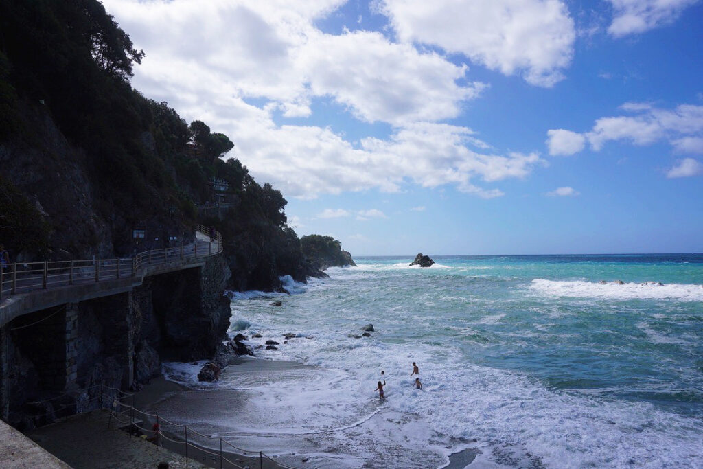 people playing in the water at the beach of monterosso al mare italy