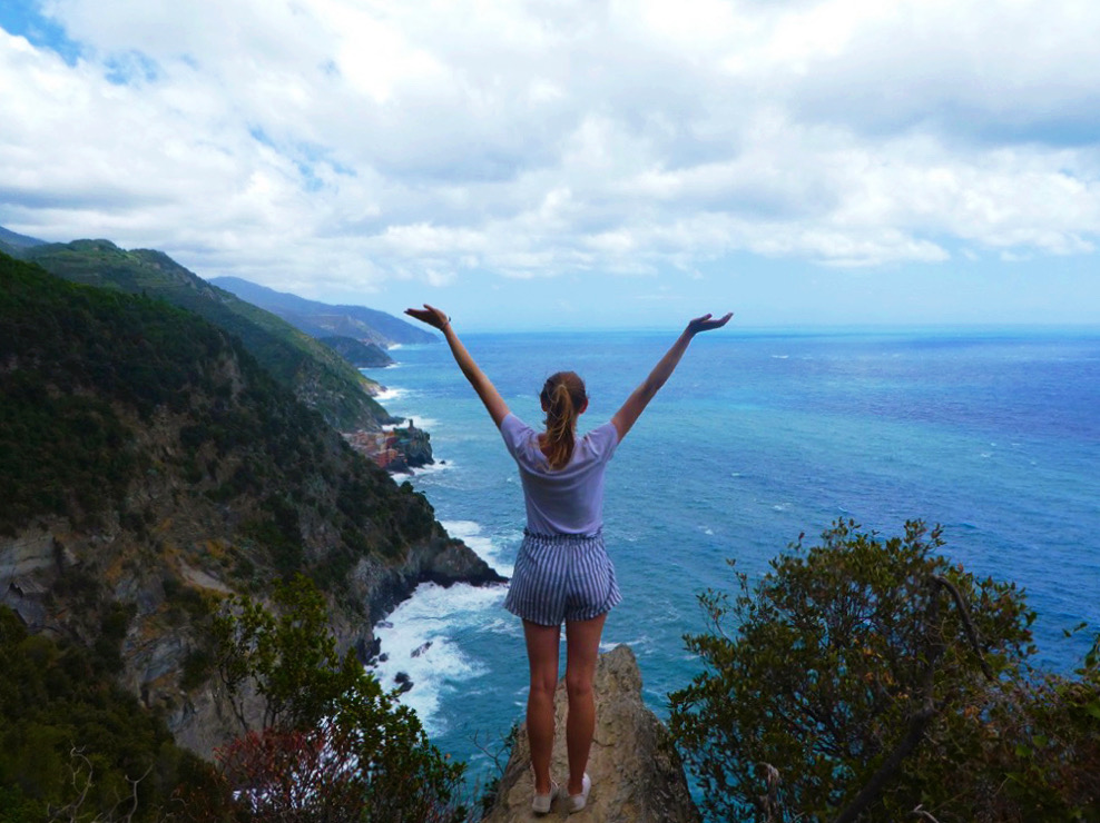 girl posing with her arms in the air on the coast of cinque terre