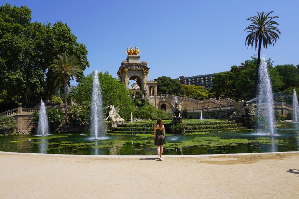 girl in a green dress looking up at the architecture of ciutadella park