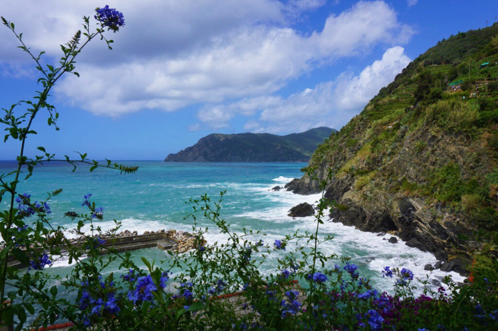 beauitful white wake of blue ocean next to cinque terre mountains
