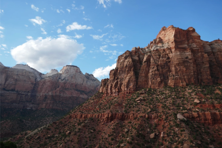 red rock mountain covered with specks of green plants
