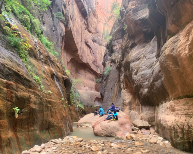 people on big rocks in the narrow river