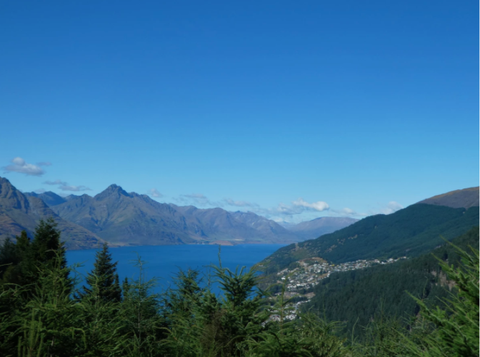 mountains behind blue lake with green trees in front