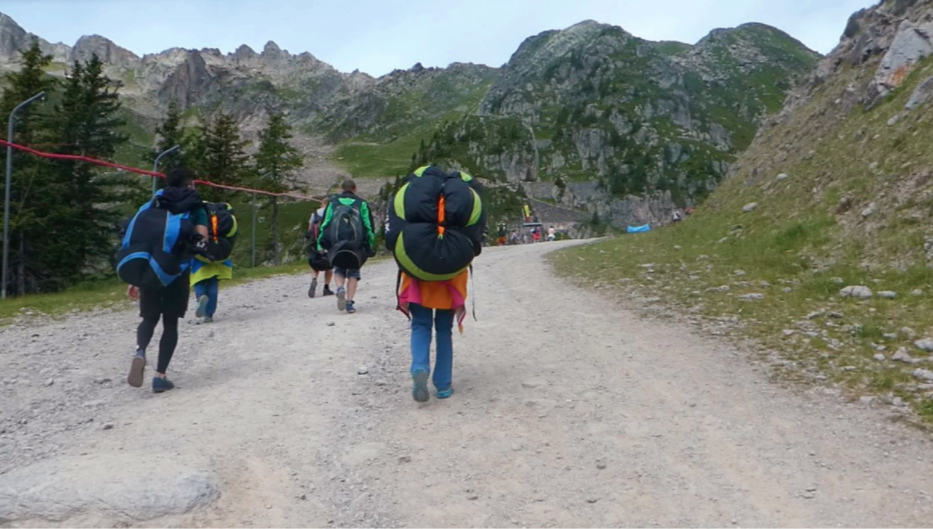 parachuter with backpack on walking up the mountain