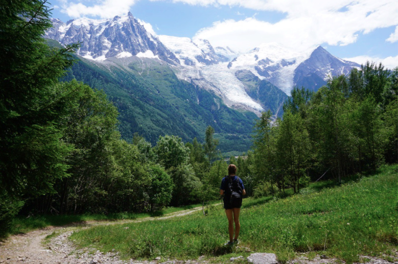 girl standing in grass field in front of mont blanc mountain