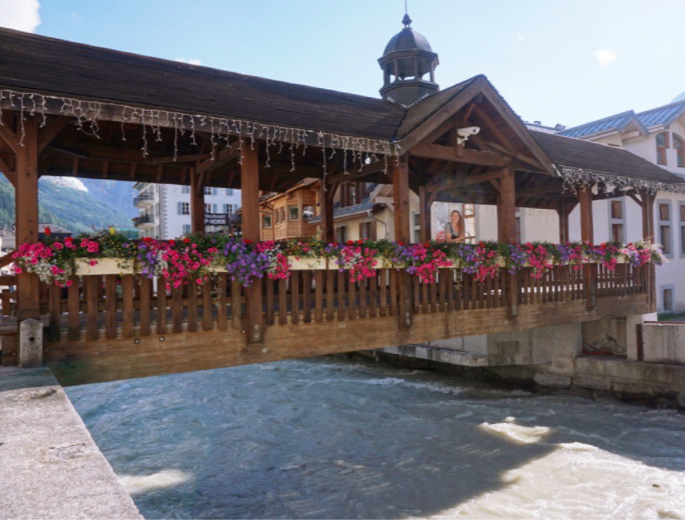 girl standing behind flowers in wooden covered bridge