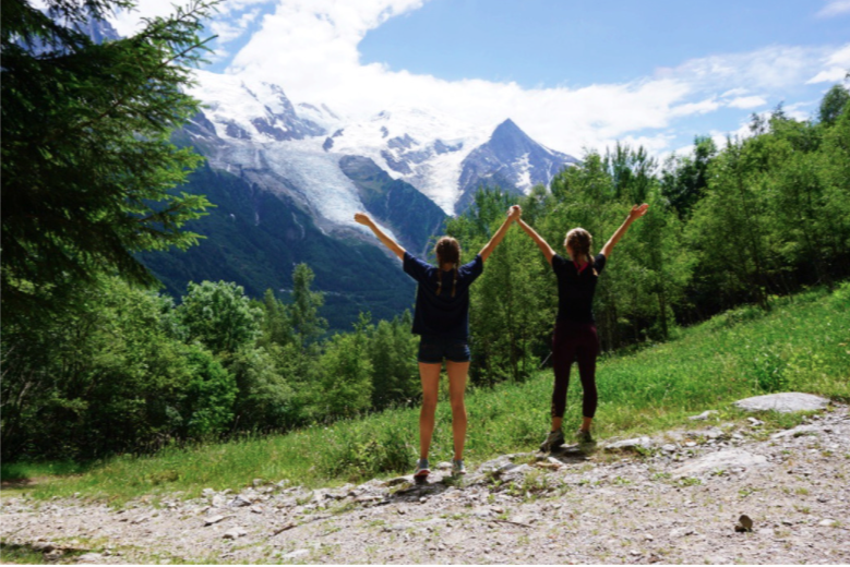 two girls holding hands in front of snow capped mountains