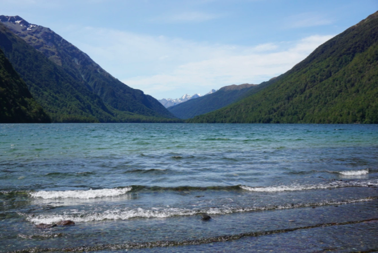 light blue lake with mountains in the background