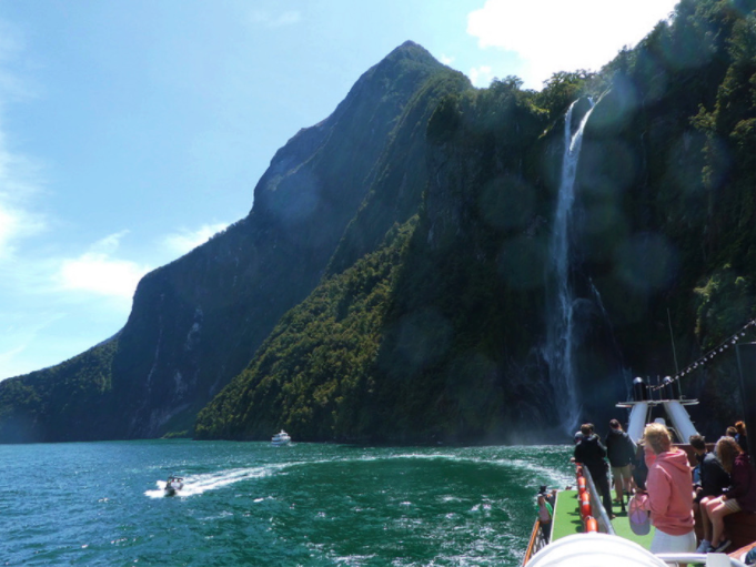 stirling falls from a boat tour of milford sound with people looking out from the boat