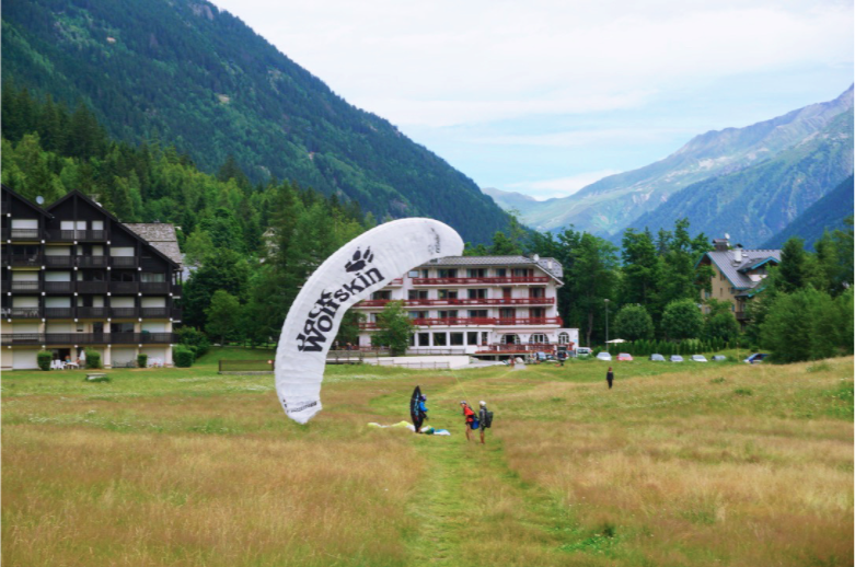girl and paraglide instructor landing in a field with a white parachute