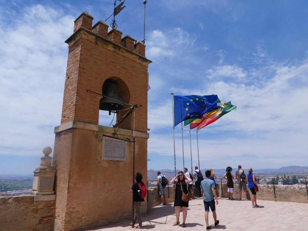 flags blowing in the wind next to an arched tower