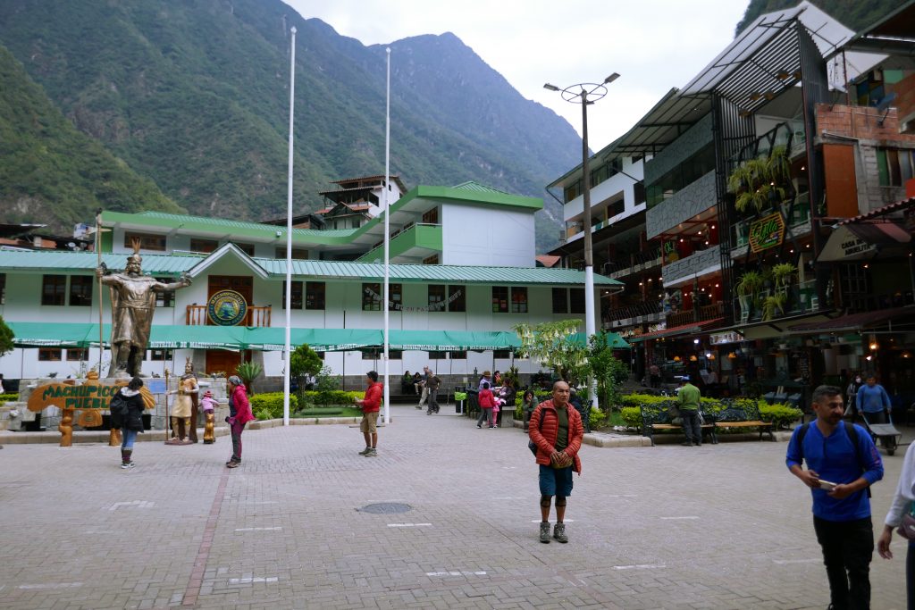 wide hotel with people walking in the plaza in front of it
