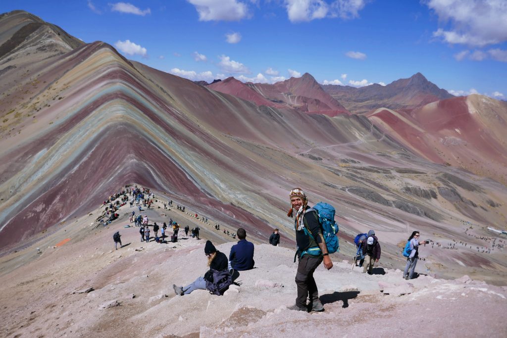 tour guide with hiking backpack at the top summit of rainbow mountain