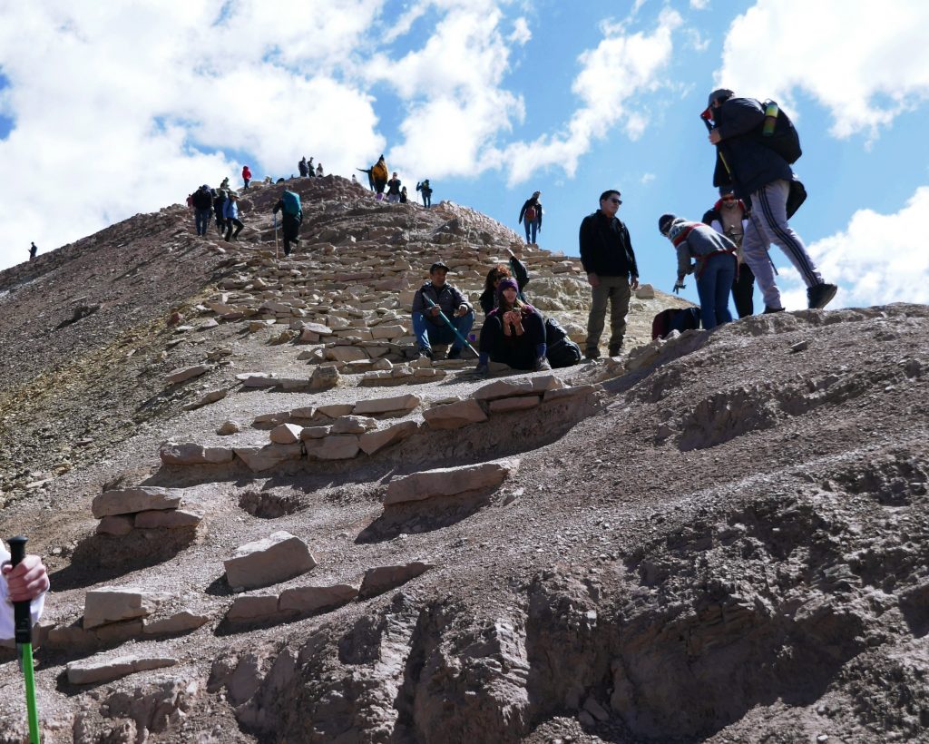 steep rocky path on the way up rainbow mountain with tourists sitting to rest