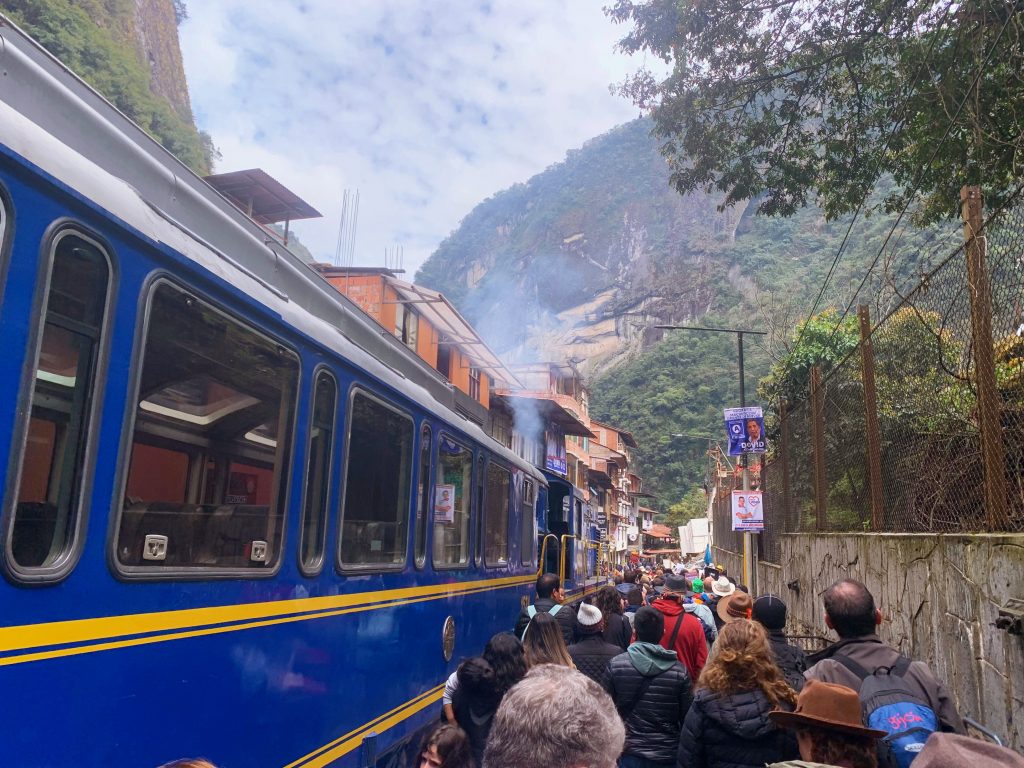 the PeruRail train station with people crowding around blue train