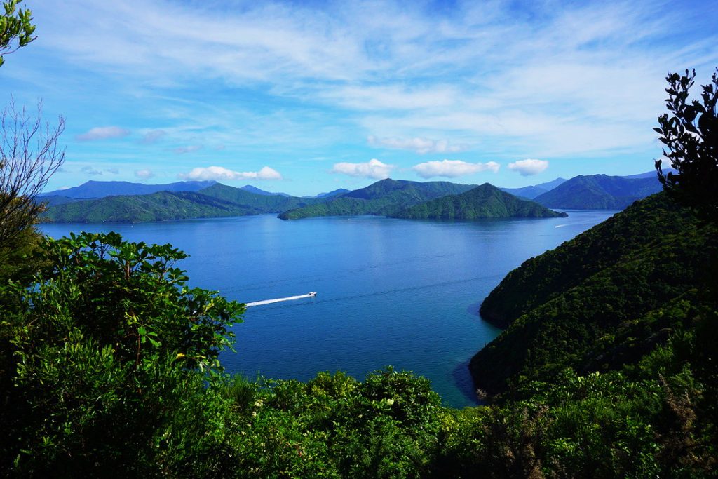 speed boat driving through blue ocean water between green mountains