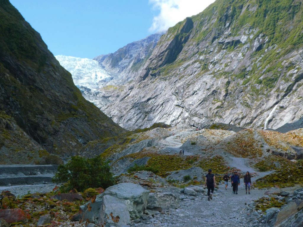 close up photo of tourists walking to franz josef glacier