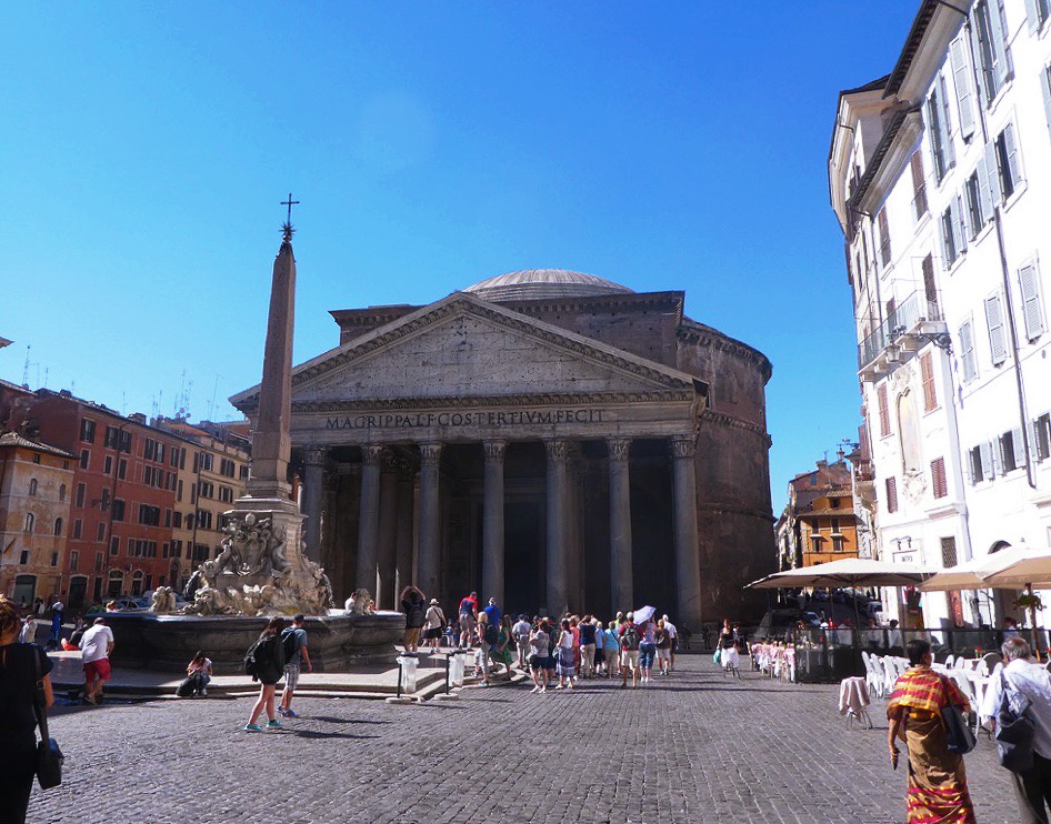 pantheon with columns at entrance behind a city square with people walking around
