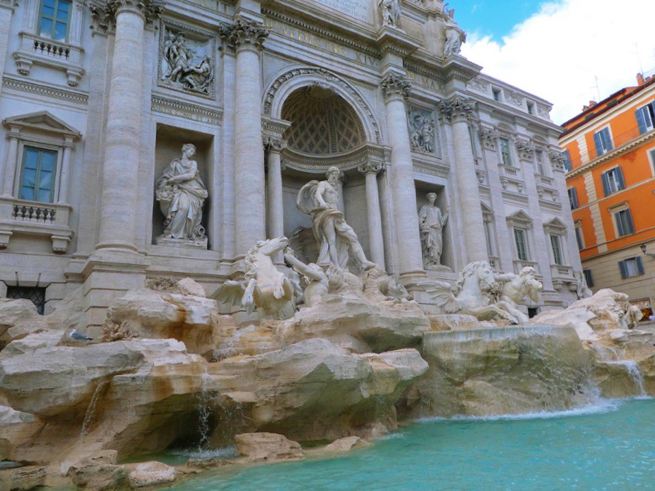 statues and columned building in front of fountain
