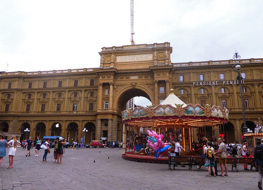 carousel with tourists walking around it in the plaza