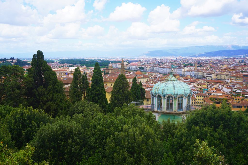 old blue dome above green trees in front of florence backdrop