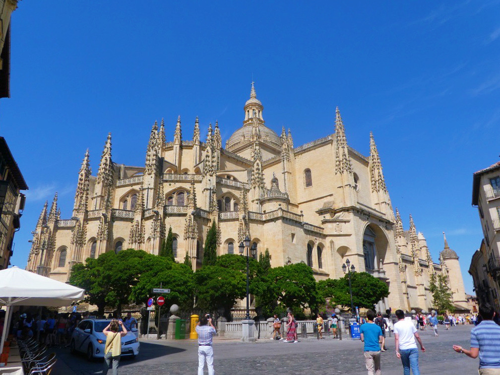 tan walls of the cathedral of segovia with tourists walking below