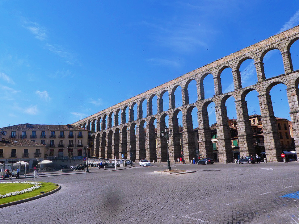 tall stone arches of the segovia aqueduct as seen from the street