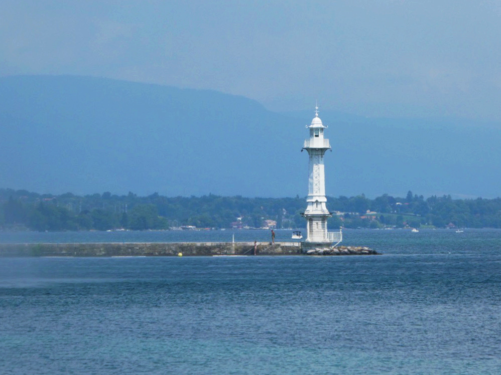 white lighthouse on blue lake