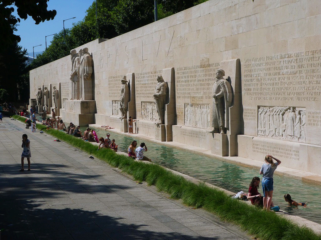 statues of men in front of a pool
