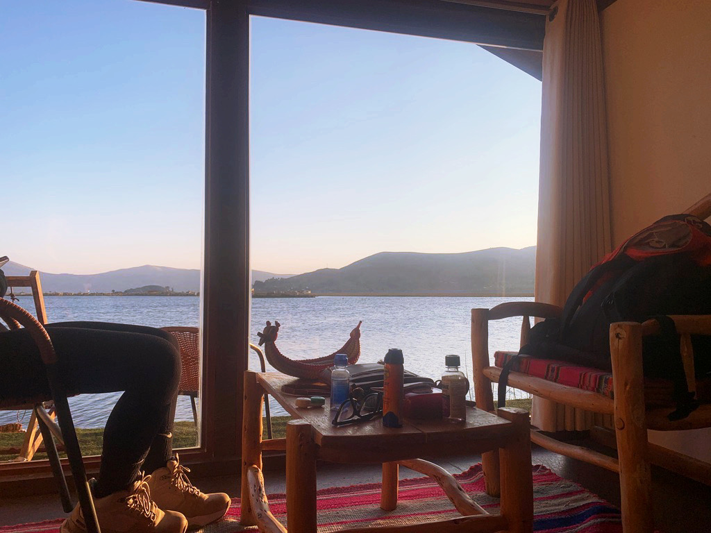 table and chair in front of glass window with lake titicaca in background