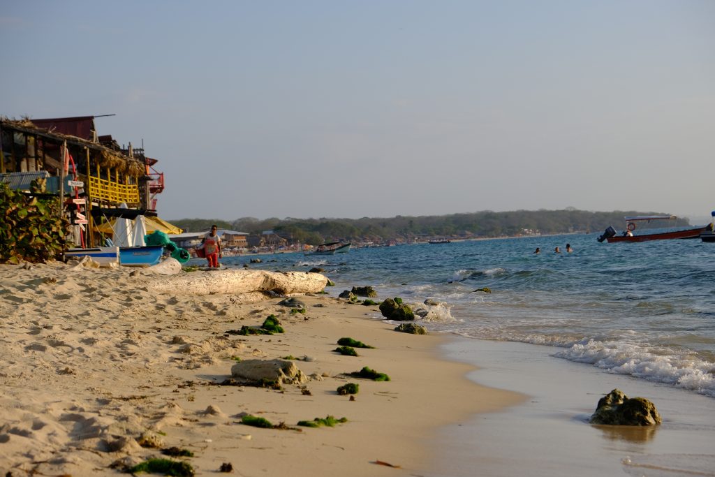 man walking along the beach before sunset where the sand meets the water in Cartagena Colombia