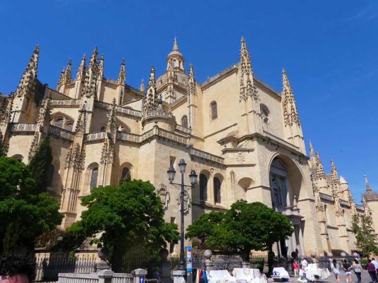 detailed architecture of the cathedral of segovia with blue sky and green trees