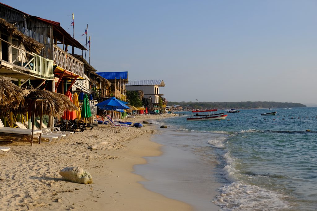 a row of colorful structures along the shoreline of the beaches of Cartagena at the end of the day before the sun goes down