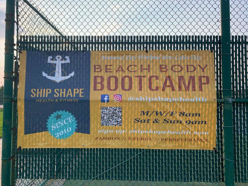 yellow sign on fence that says beach body bootcamp