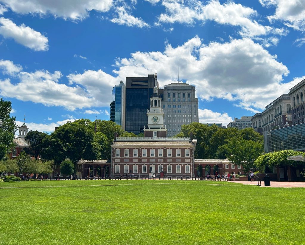green lawn in front of independence hall philadelphia with clouds and blue sky in the background