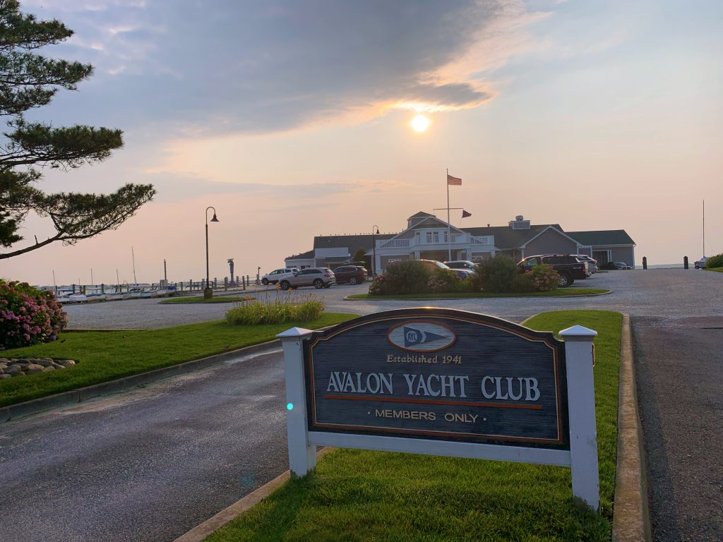 sign that says yacht club at sunset