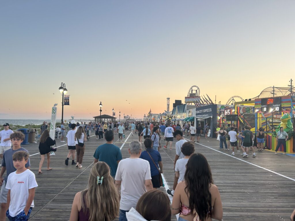 boardwalk with a lot of people walking on it at sunset
