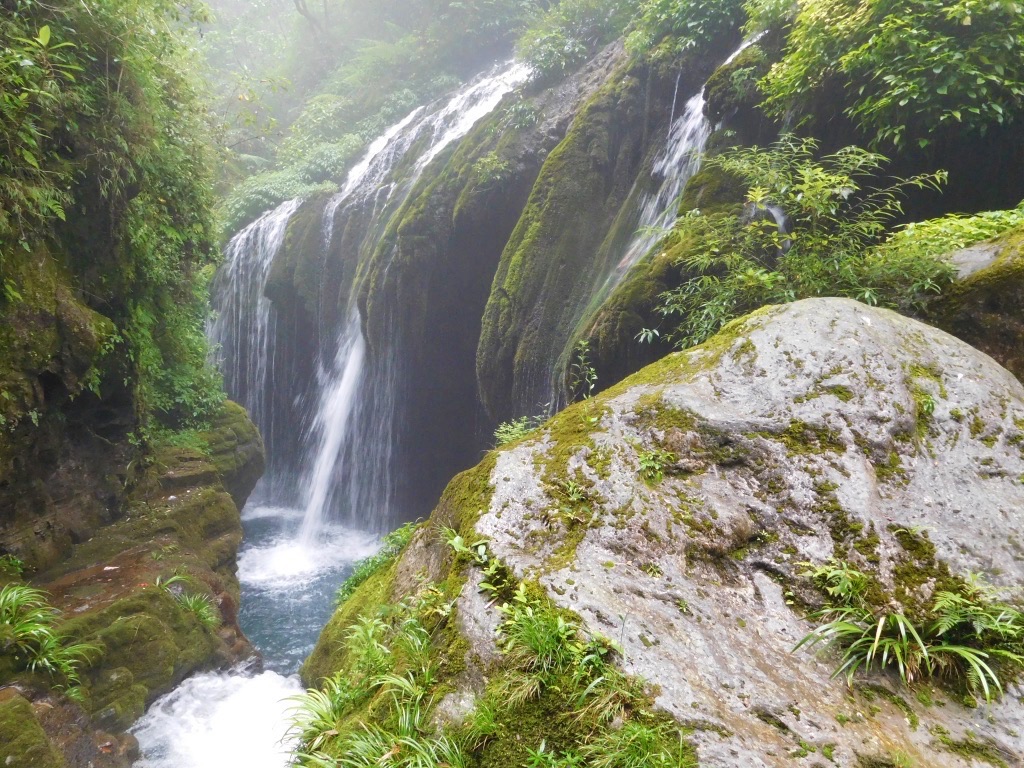 waterfall pouring into blue pool of water in the jungle