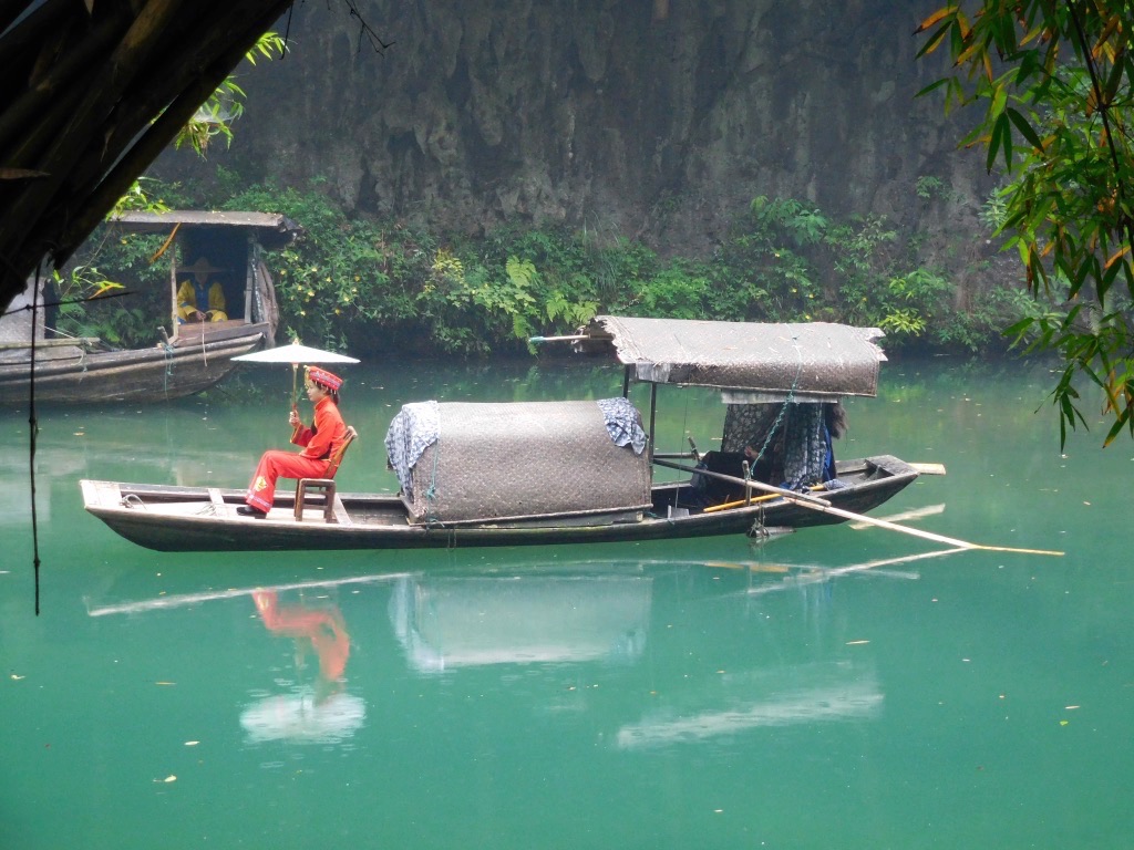 woman in red traditional clothing sitting under umbrella on fishing boat