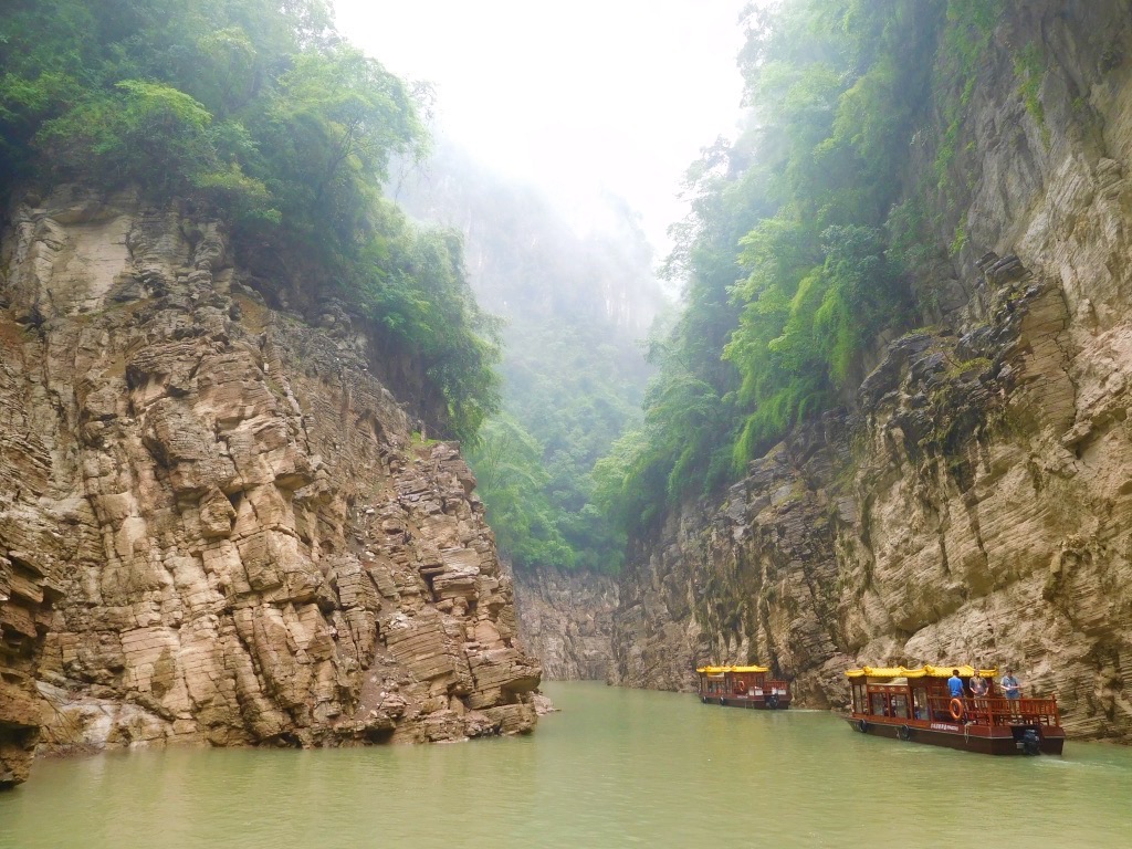 light green water in a narrow stream with brown rocks and green trees on each side