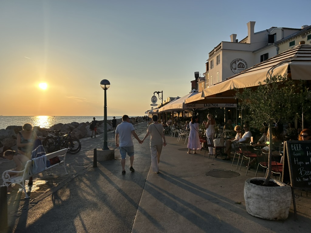 couple walking along the piran promenade at sunset