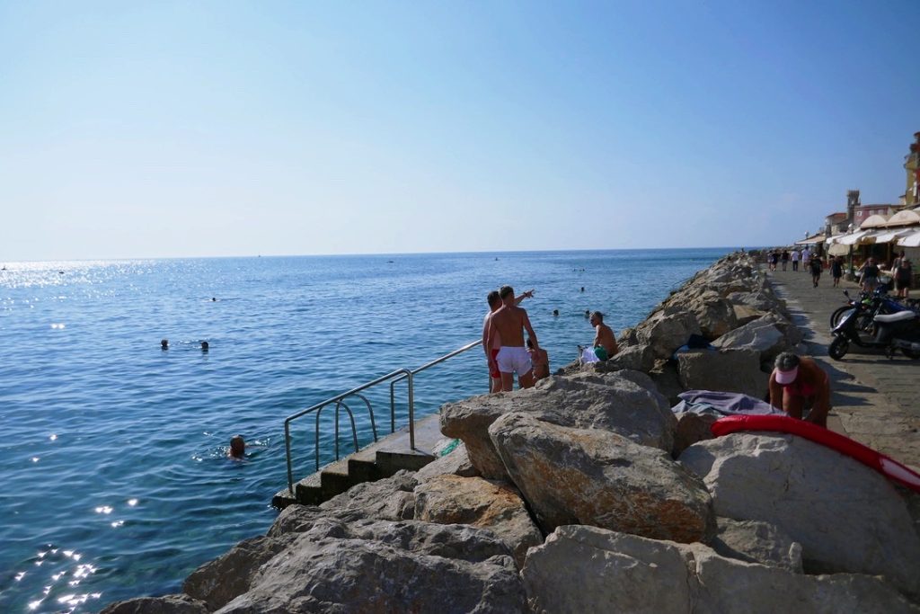 view of people swimming from the rocks in piran