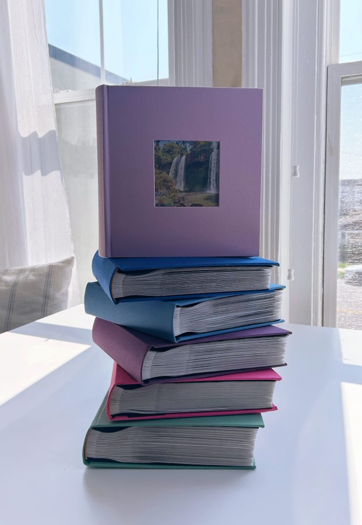 stack of six colorful photo albums sitting on a table