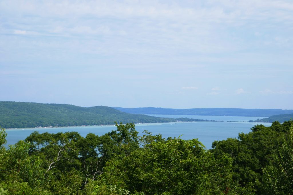 tree covered sand dune in the midst of a blue lake