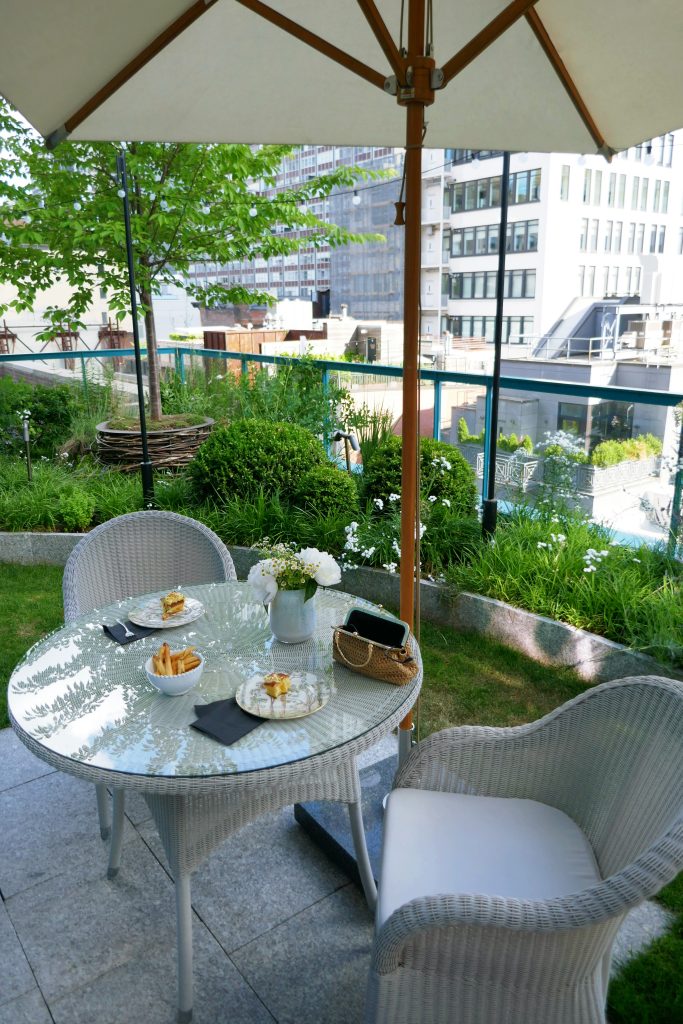 lunch on a table with two chairs and flowers and a purse