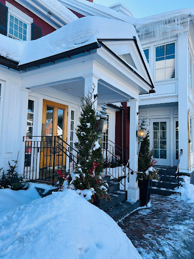 columned entrance to a white inn with trees in front and snow on the building